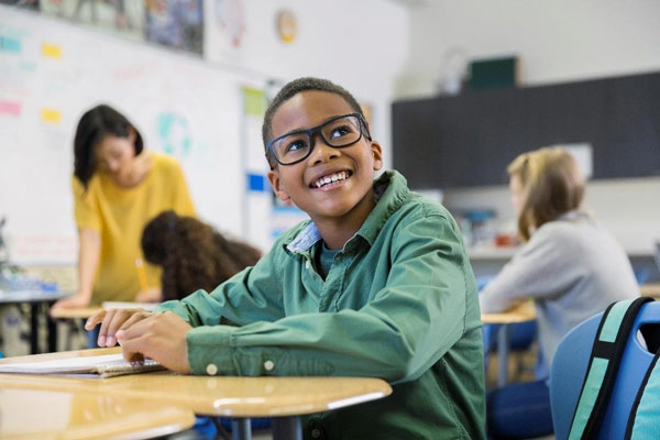 boy with glasses on smiling in classroom